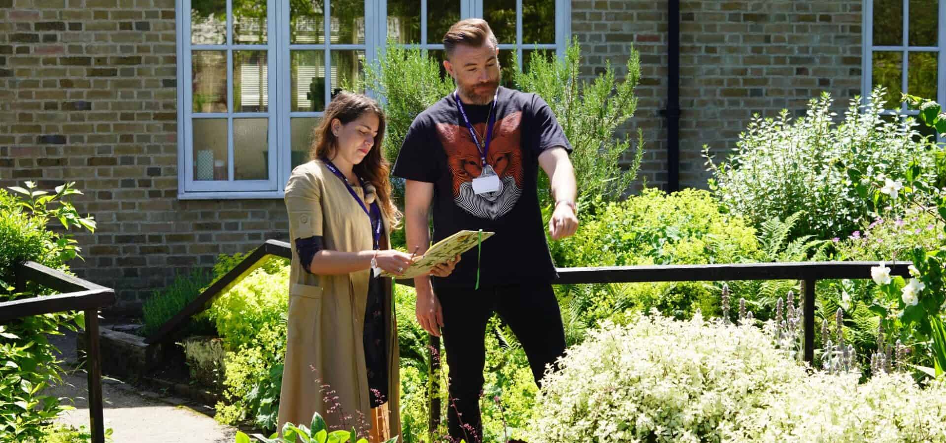 Photo of a man and women looking at a garden and making notes