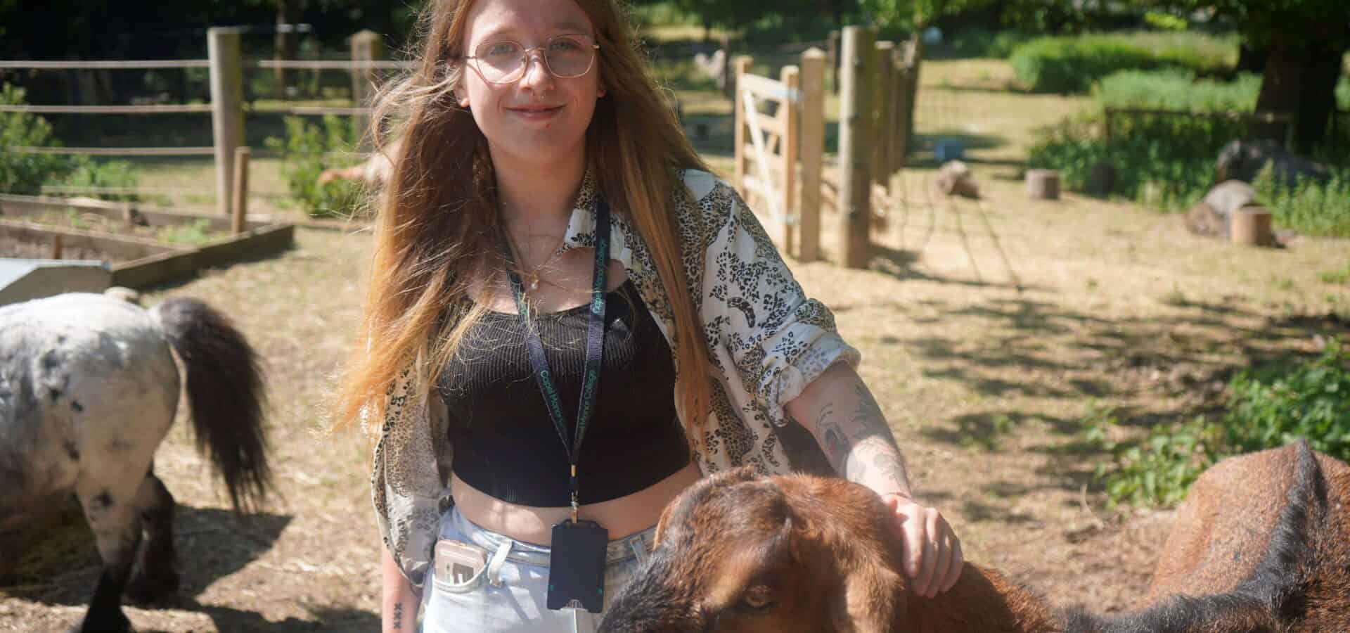 Image of Capel Manor College success story animal management student at Crystal Palace Park Farm, stroking a goat.