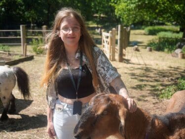 Image of Capel Manor College success story animal management student at Crystal Palace Park Farm, stroking a goat.