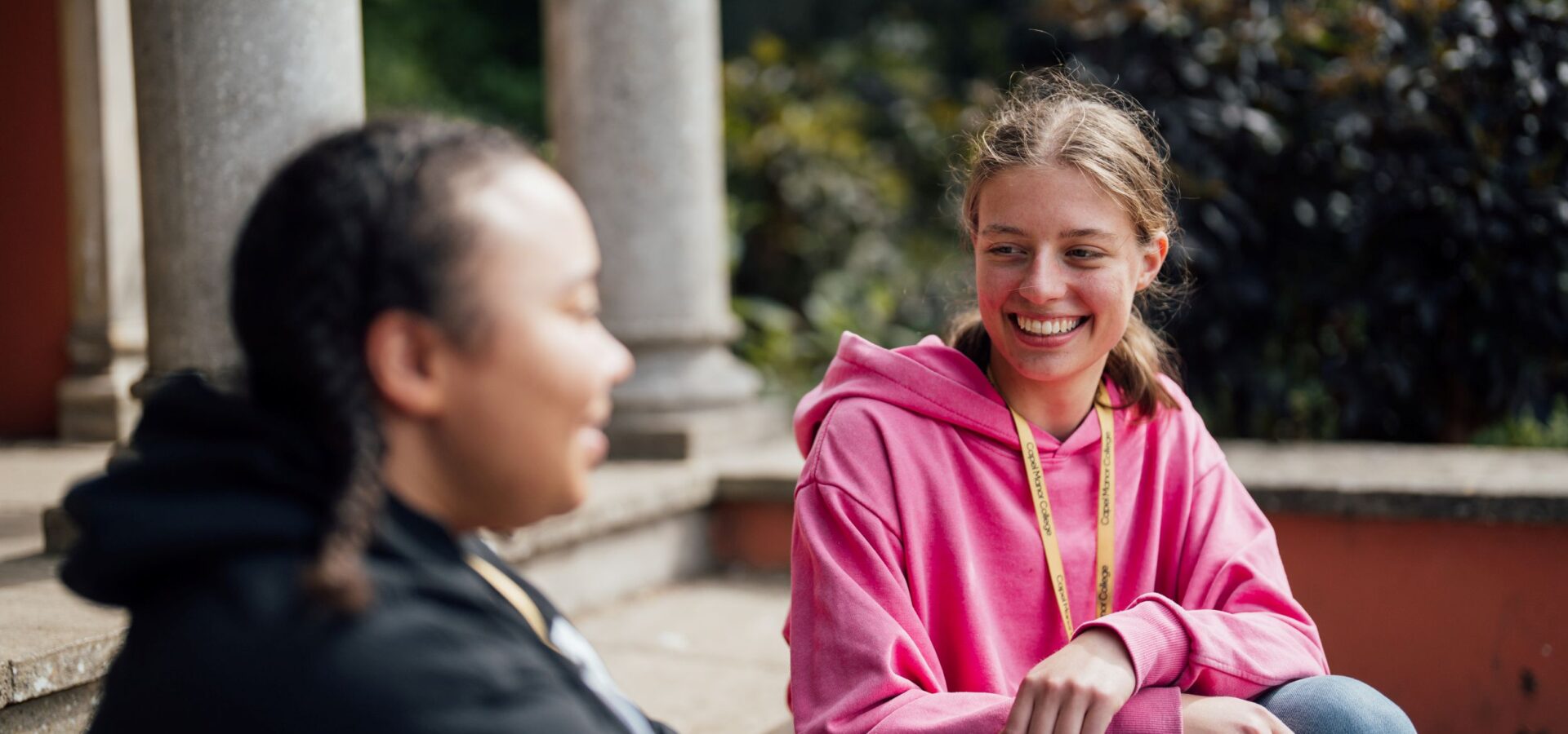 Two Capel Manor College students sitting in the grounds of the Enfield Campus, chatting.