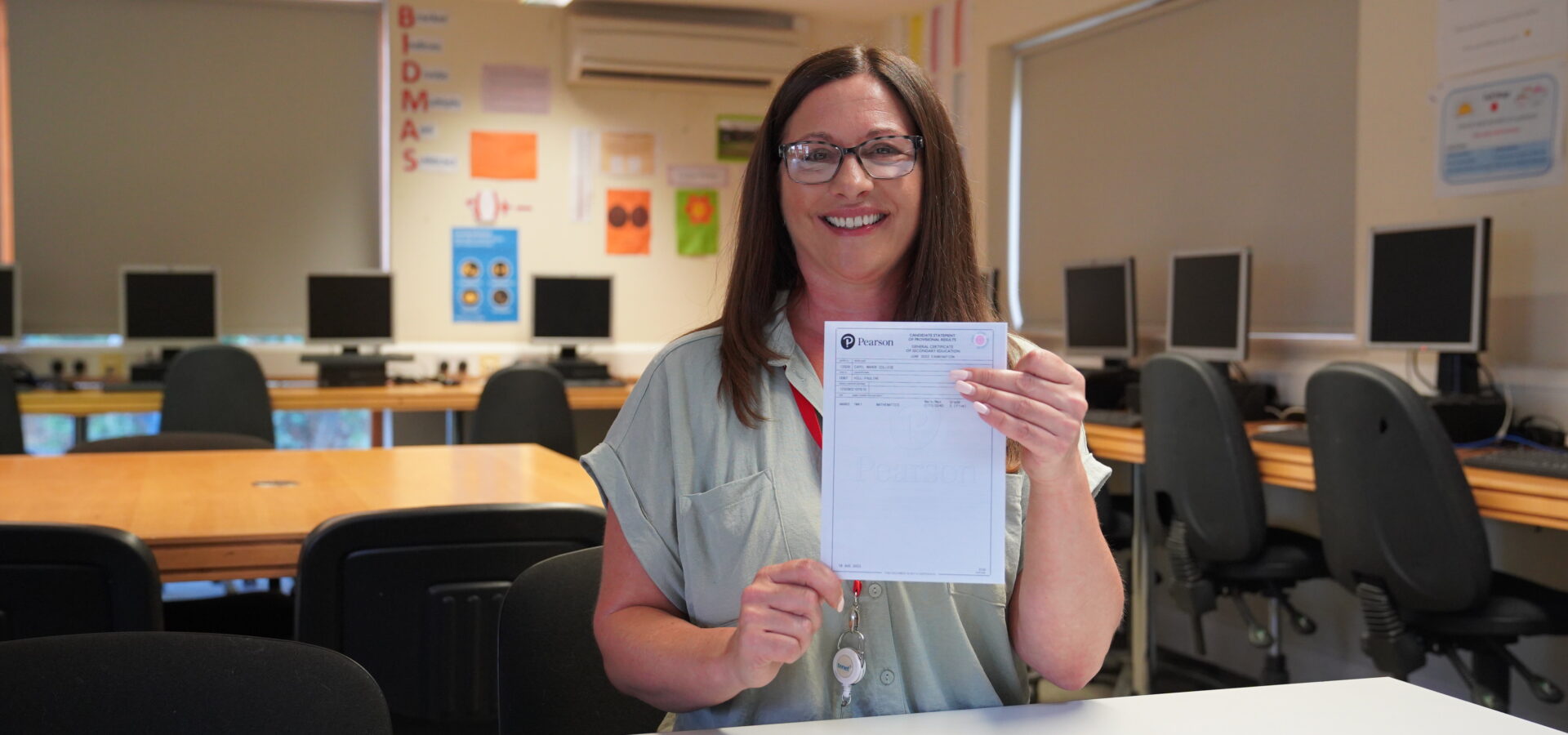 An adult learner at Capel Manor College smiling with their GCSE maths certificate.