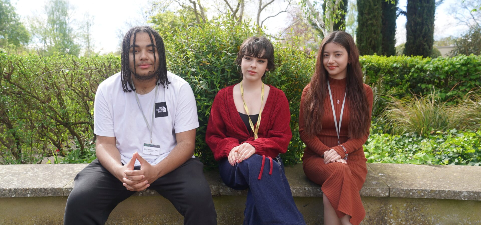 Three maths and English students at Capel Manor College sitting down to have their photo taken after a competition win.