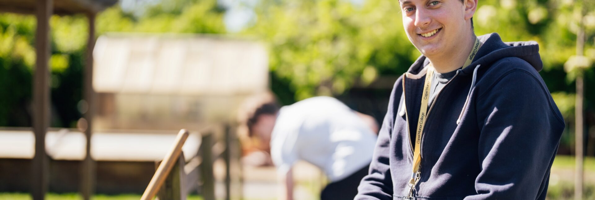 Horticulture student at Capel Manor College smiling with his hand on a spade.
