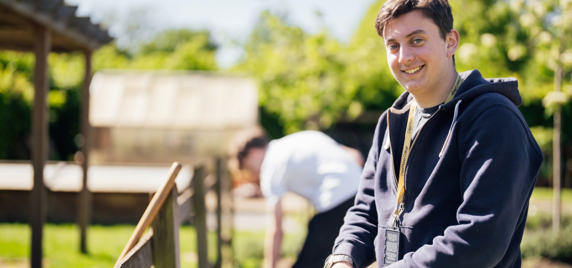 Horticulture student at Capel Manor College smiling with his hand on a spade.