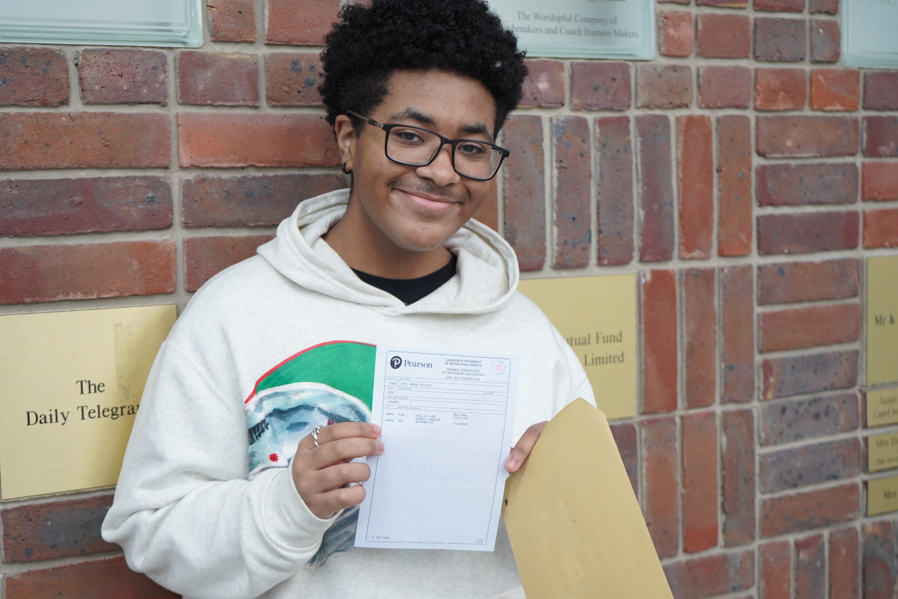 Capel Manor College student holding up their maths and English GCSE certificate.