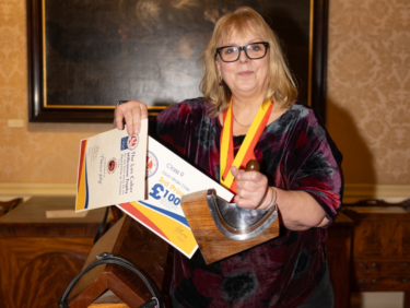 A saddlery and shoemaking (leatherwork) student from Capel Manor College in London, holding her recent award wins.