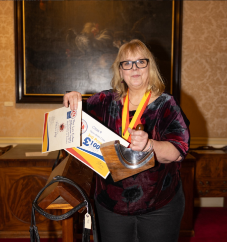 A saddlery and shoemaking (leatherwork) student from Capel Manor College in London, holding her recent award wins.